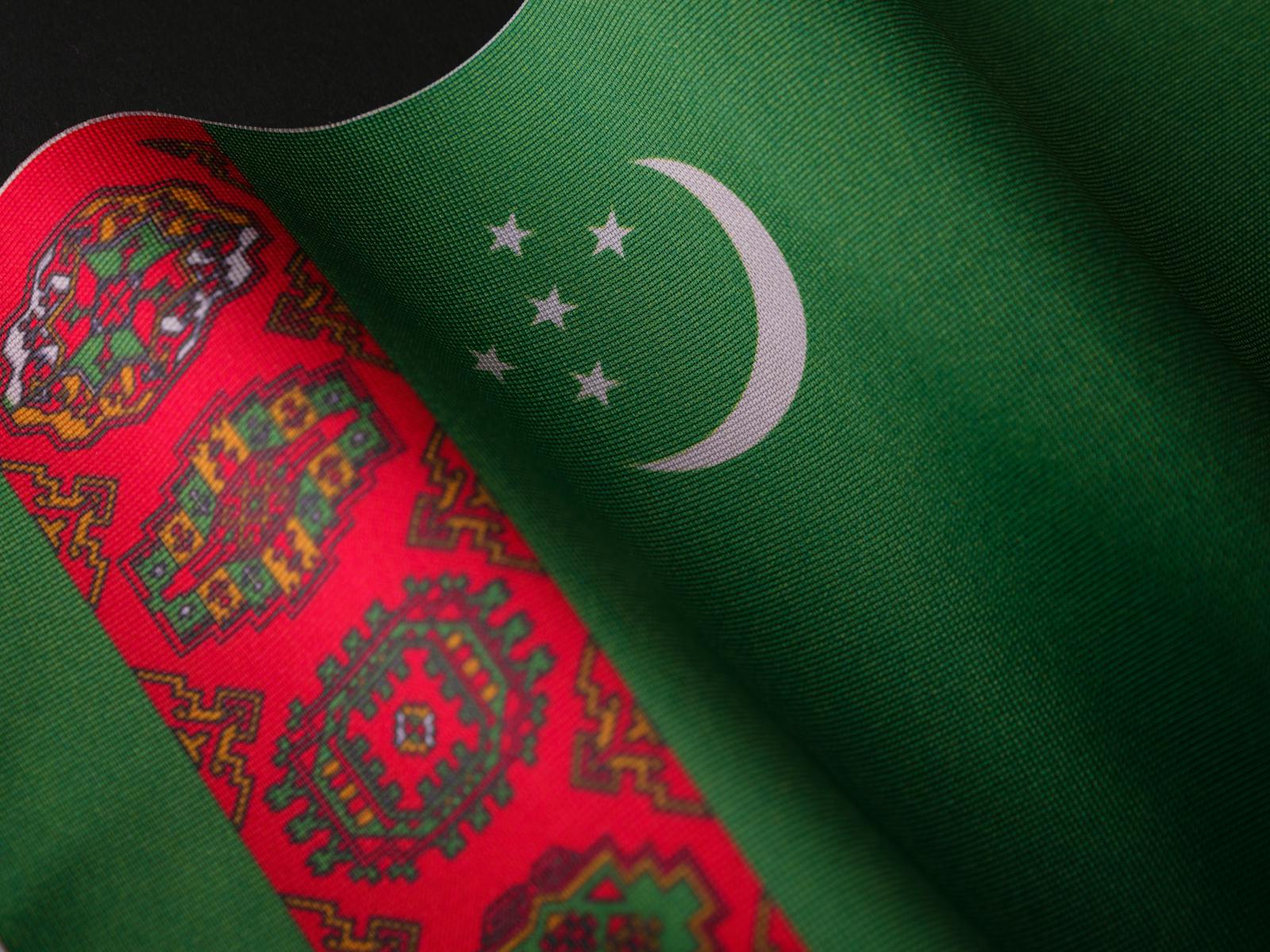 Detailed close-up of the Turkmenistan flag with its intricate patterns and vibrant colors.