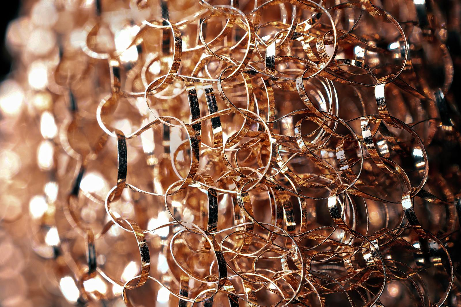 Close-up of intricate metallic wire art featuring a mesmerizing golden bokeh effect, perfect for abstract and creative projects.