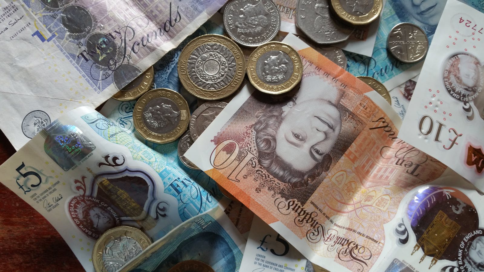 Close-up collection of British Pound notes and coins, showcasing UK currency.