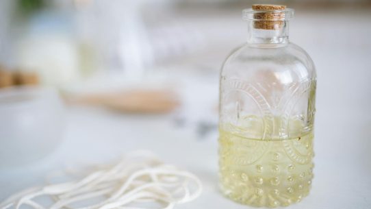 Artisan candle crafting scene with a glass bottle, wick, and aromatic wax ingredients.