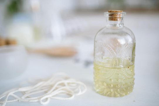 Artisan candle crafting scene with a glass bottle, wick, and aromatic wax ingredients.