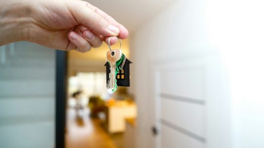 Holding house keys in front of the entrance.