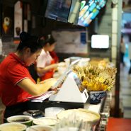 Workers at a counter in a busy restaurant.