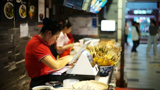 Workers at a counter in a busy restaurant.
