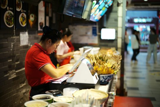 Workers at a counter in a busy restaurant.