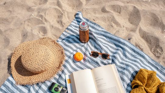 brown glass bottle beside white book on blue and white textile