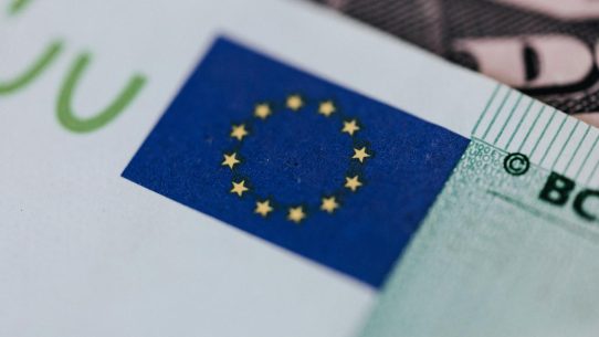 From above of crop banknote of European Union placed on table with dollars