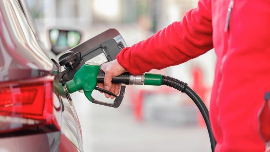 a person filling a car with gas at a gas station