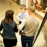 man, woman, and child standing on escalator