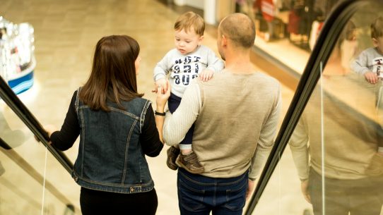man, woman, and child standing on escalator