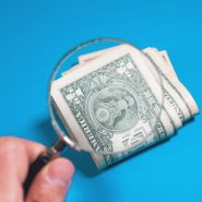 Magnifying glass over folded us dollar bills
