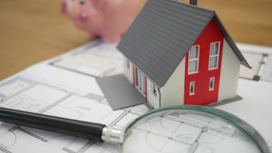 white and red wooden house beside grey framed magnifying glass
