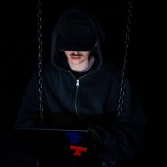 A figure is using a laptop in the dark.