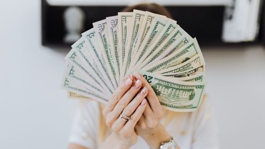 Close-up of hands holding a fan of US dollar bills, showcasing financial abundance.