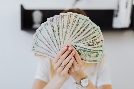 Close-up of hands holding a fan of US dollar bills, showcasing financial abundance.