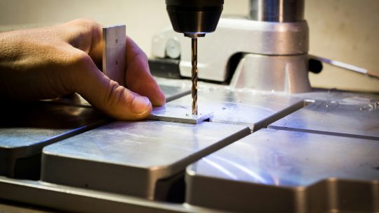 person drilling metal bar