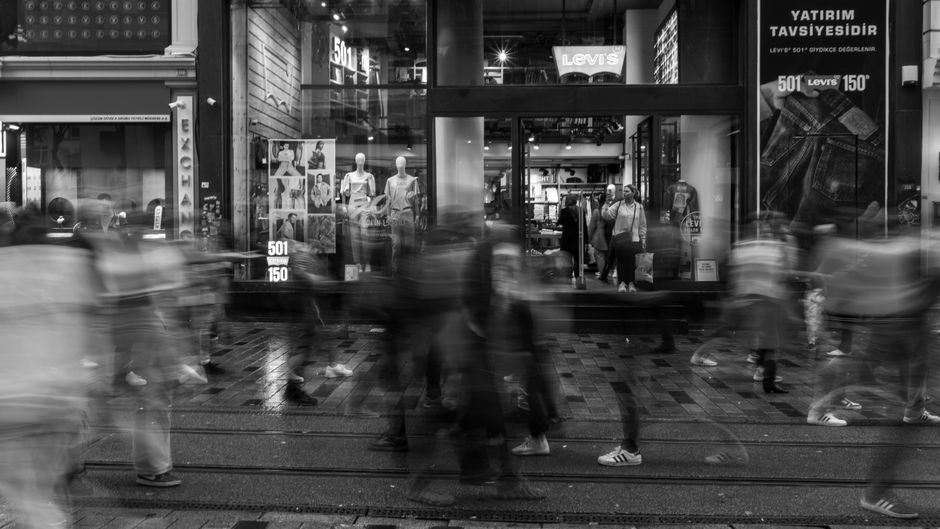 A busy urban street with blurred pedestrians and a storefront at night.