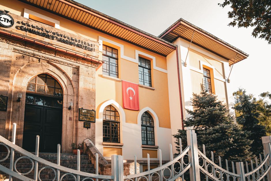 Facade of Anadolu University Cultural Center in Turkey with national flag under golden sunlight.