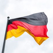Vibrant German flag flying against a backdrop of a cloudy sky, symbolizing national pride.