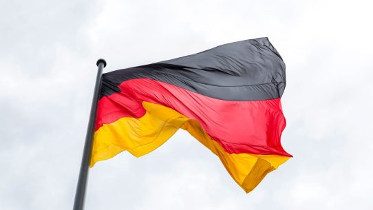 Vibrant German flag flying against a backdrop of a cloudy sky, symbolizing national pride.