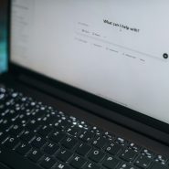 A laptop displays "what can i help with?"