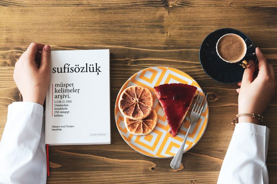 A top view of coffee, cake, and a book on a wooden table, creating a cozy breakfast scene.