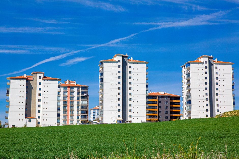 Contemporary apartment buildings amidst a clear blue sky and green field, showcasing urban living.