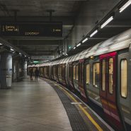 A London Underground train at a platform with a digital arrival sign