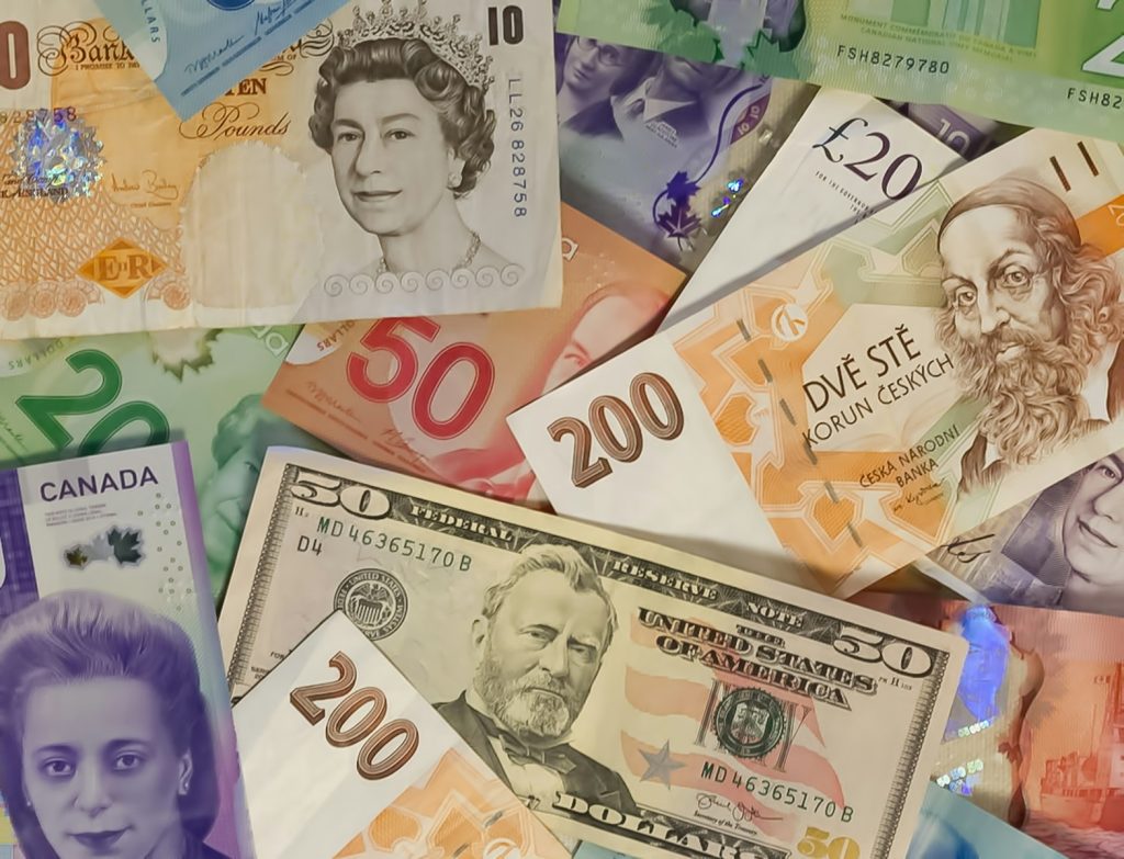 A collection of international banknotes including US dollars, British pounds, and Czech koruna