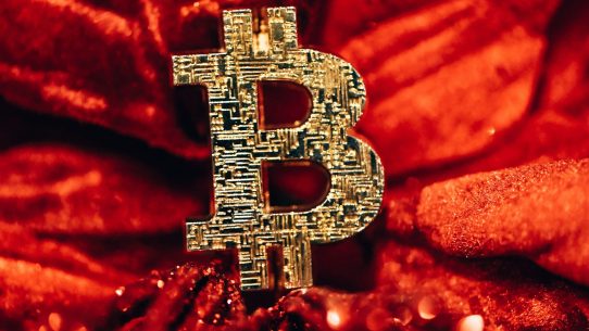 a golden bitcoin sitting on top of a red blanket