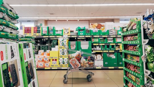 Shopping cart in a vibrant supermarket aisle in Padova, Italy.