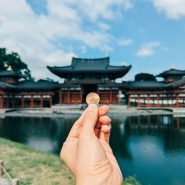 A hand holding a small piece of food in front of a body of water