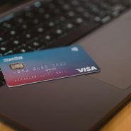 A blue and red gradient debit card resting on a dark laptop keyboard